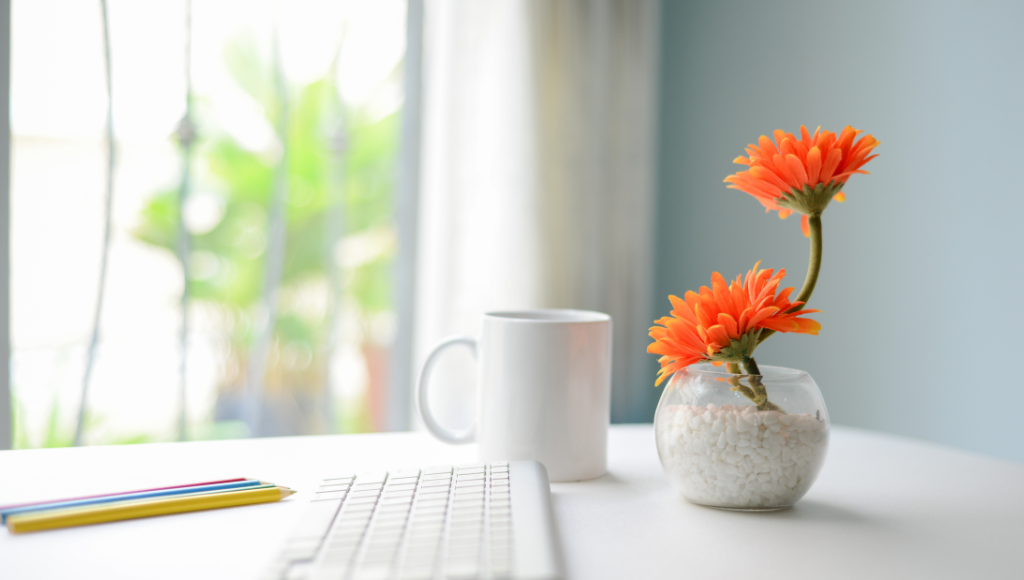 机に置いてあるキーボードとオレンジ色の花
